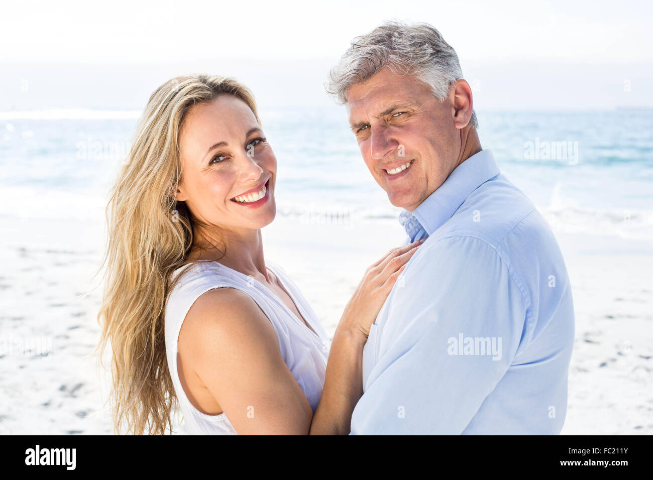 Happy couple standing by the sea and smiling at camera Stock Photo - Alamy