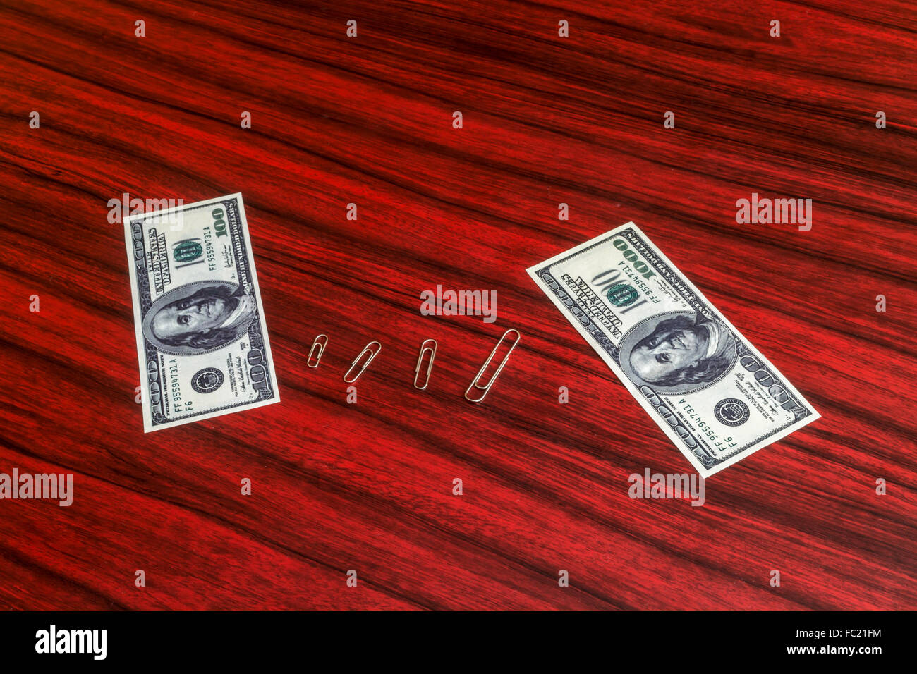 Paper clips arranged by size between 100 and 1000 dollar bill Stock Photo