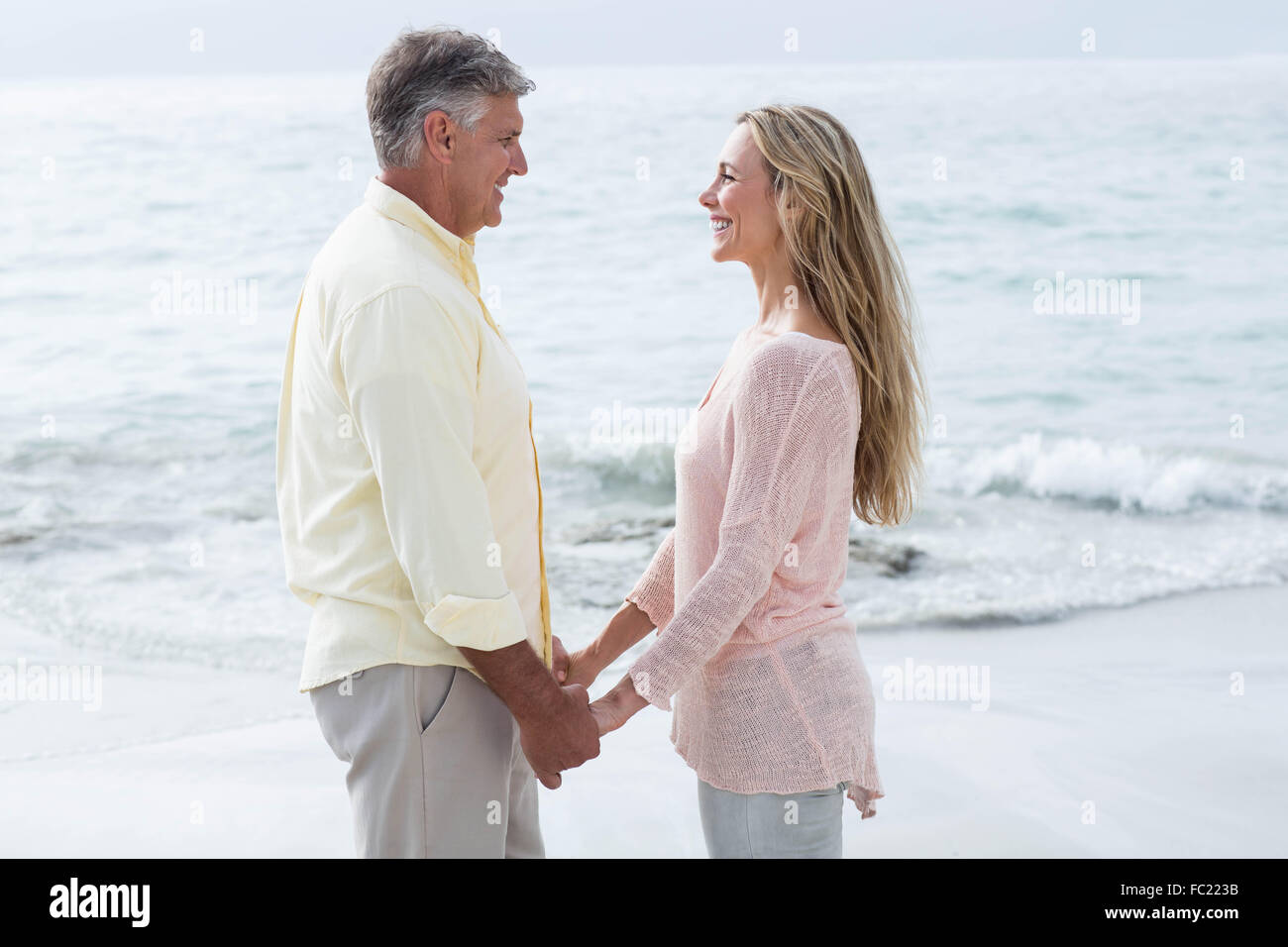 Happy couple holding hands and smiling at each other Stock Photo - Alamy