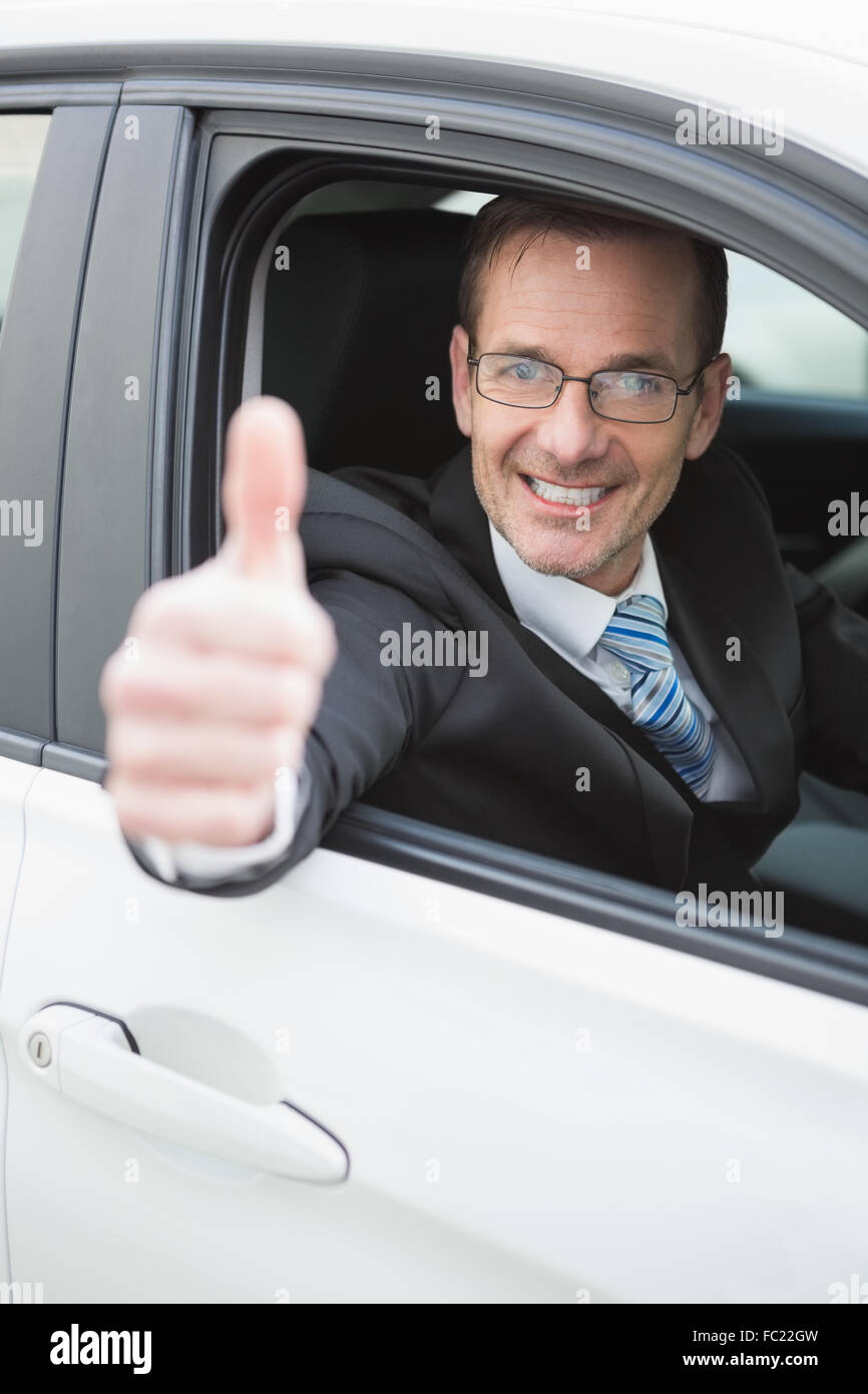 Businessman smiling at camera showing thumbs up Stock Photo - Alamy