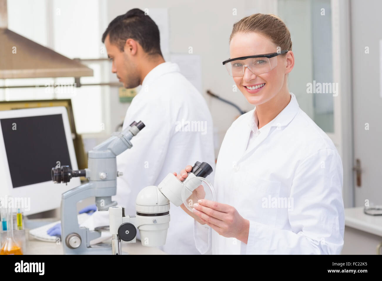 Scientist examining petri dish smiling at camera Stock Photo - Alamy