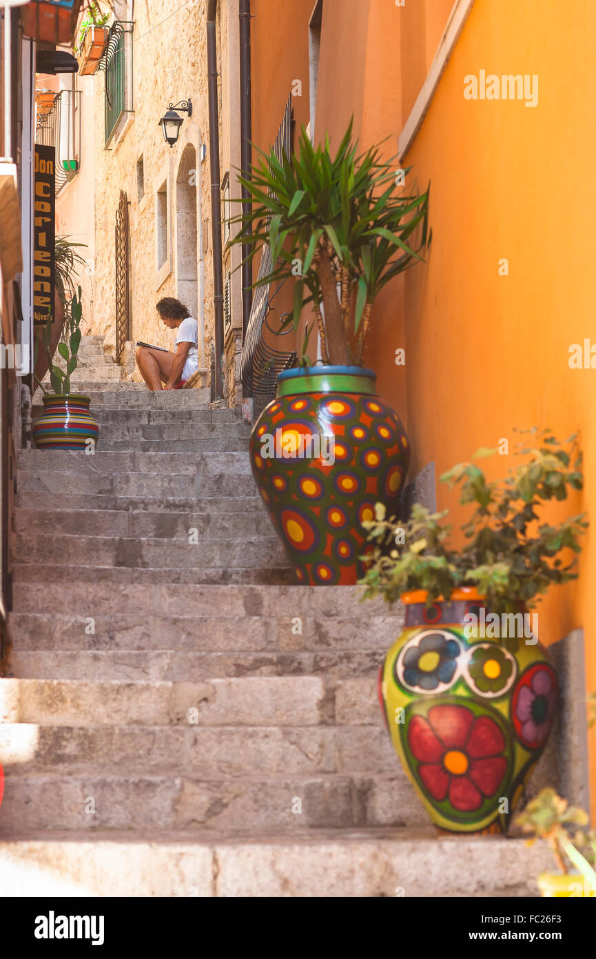 Taormina Sicily, A man reads alone in a narrow street in the old town area of Taormina, Sicily. Stock Photo