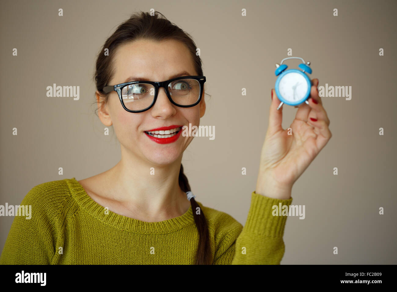 Little blue alarm clock in the hands of an emotional young woman, concept of saving time Stock Photo