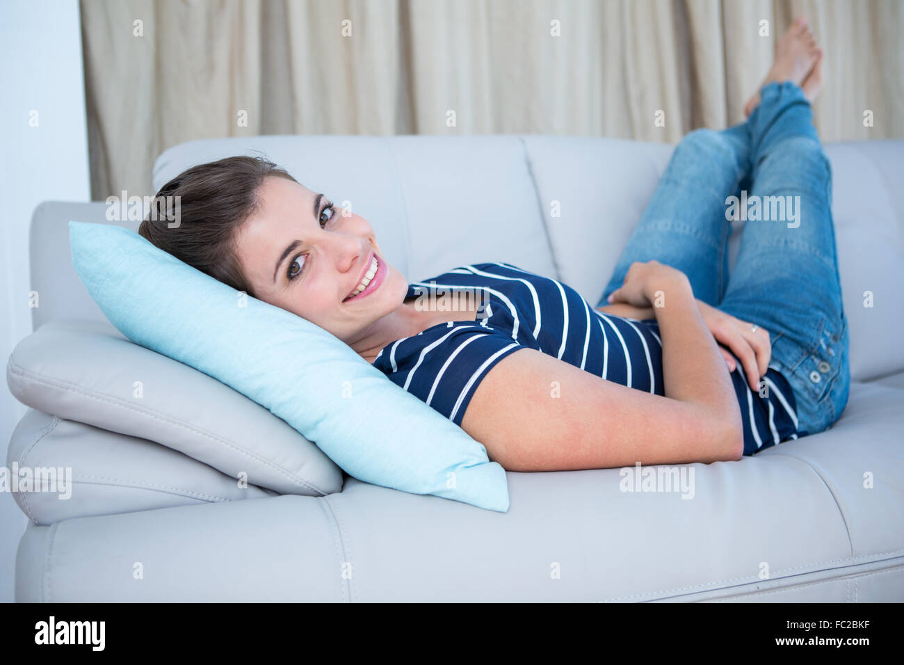 Beautiful woman lying on couch smiling at camera Stock Photo - Alamy