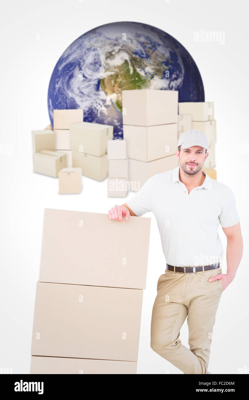 Composite image of confident delivery man leaning on cardboard boxes Stock Photo