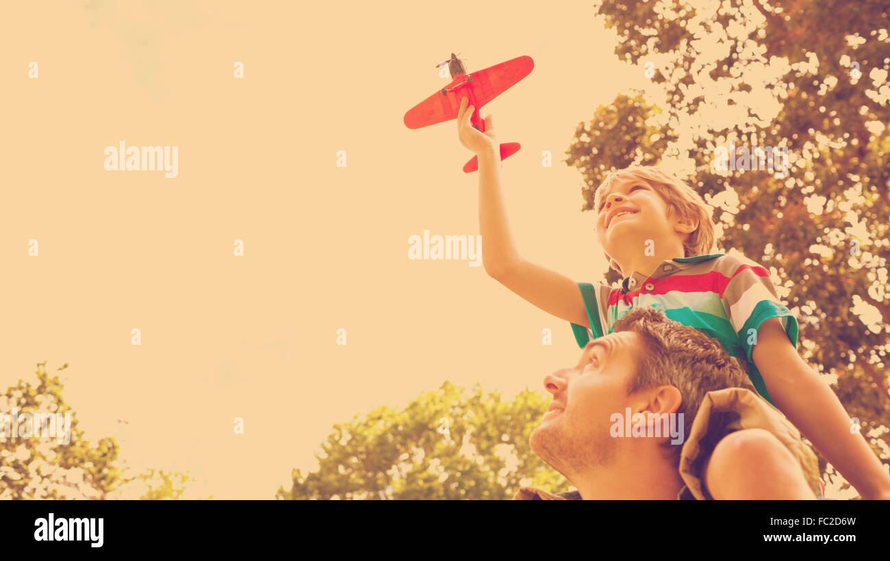 Boy with toy aeroplane sitting on fathers shoulders Stock Photo