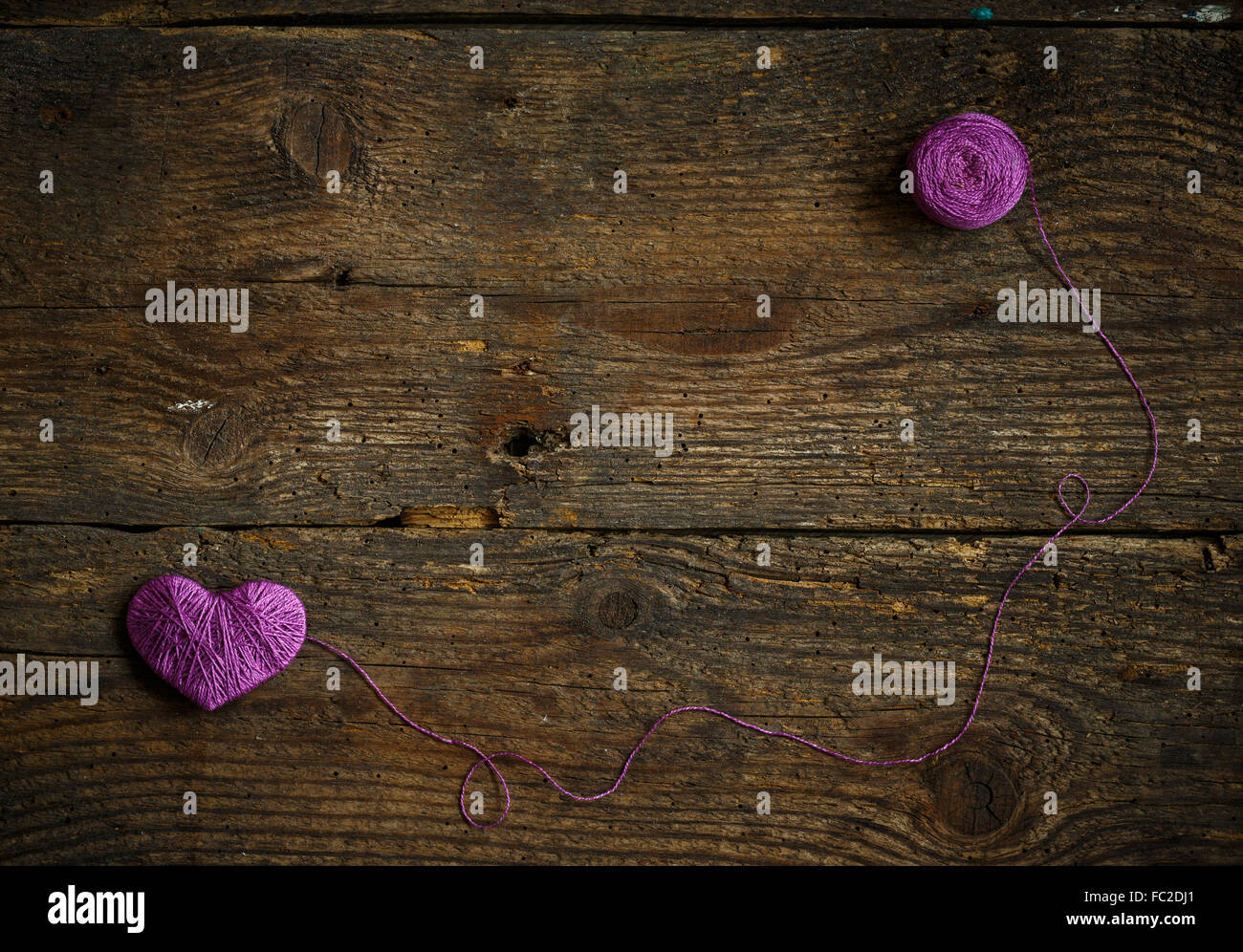 Purple Heart with a ball of thread on on old shabby wooden background ...
