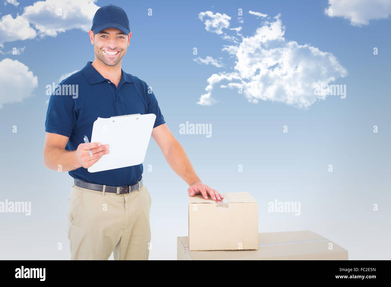 Composite image of happy delivery man with cardboard boxes and clipboard Stock Photo