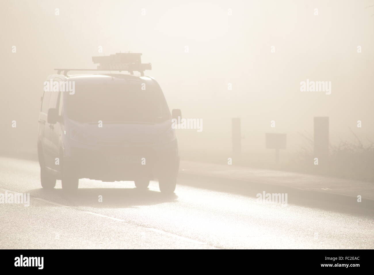 A van traveling down a road in the fog. Stock Photo