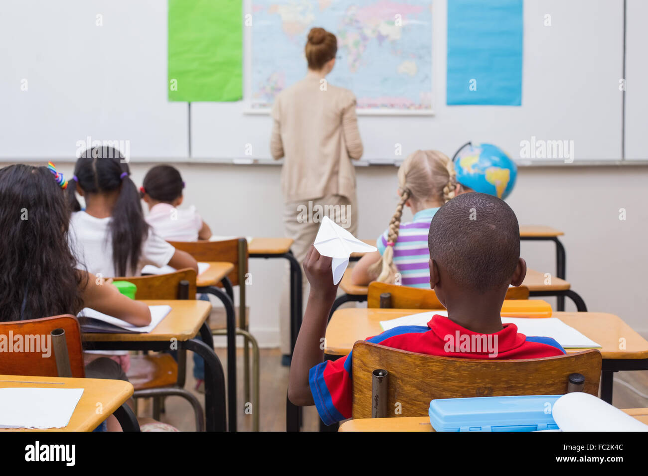 Naughty pupil about to throw paper airplane in class Stock Photo