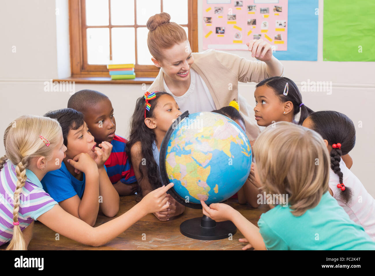 Cute pupils and teacher in classroom with globe Stock Photo - Alamy