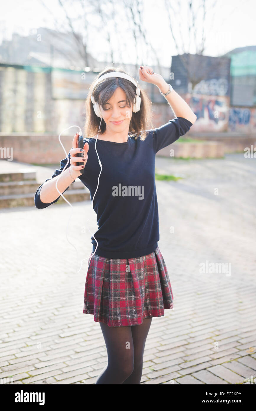 Knee figure of a young pretty brown hair caucasian girl listening music