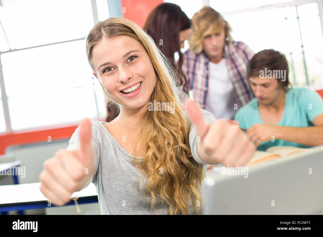 Female student gesturing thumbs up in classroom Stock Photo - Alamy