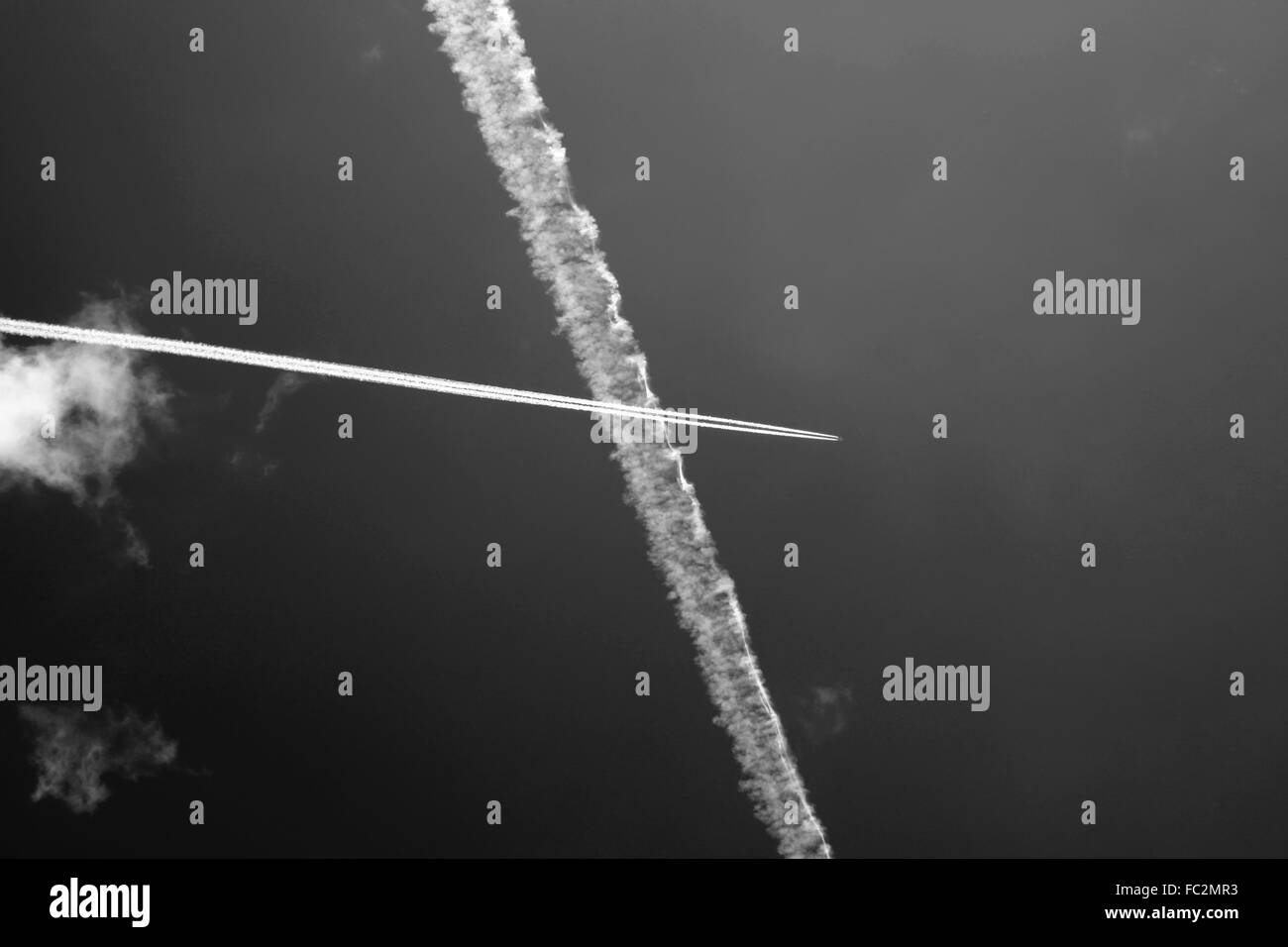 Passenger jet trails crossing in a blue sky Stock Photo