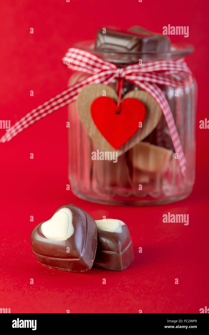Chocolates in a jar on red background. Valentines day concept Stock