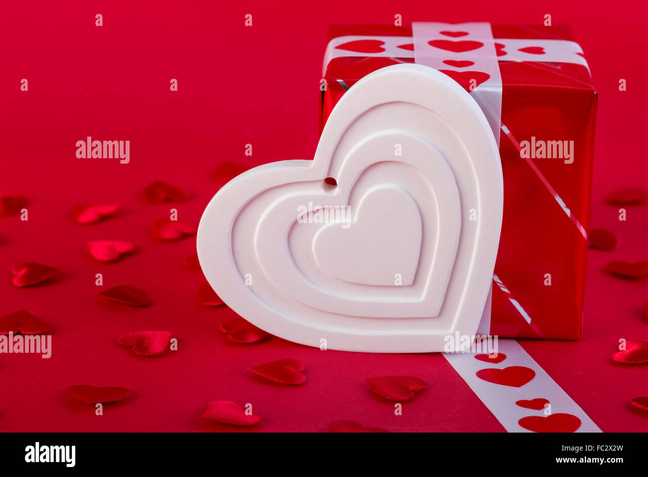 Red Holidays gift and heart on red background. Valentines day background. Stock Photo