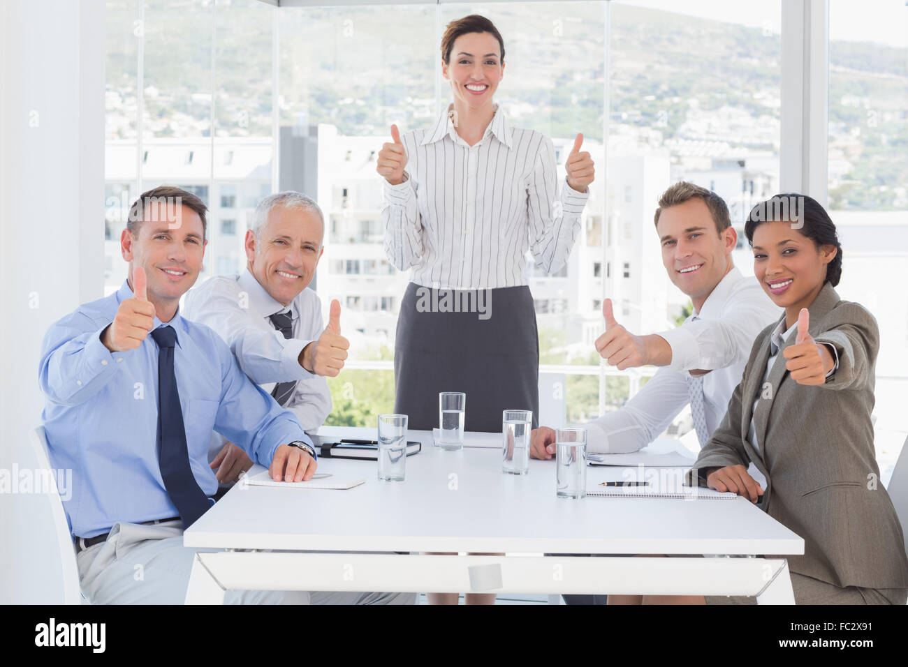 Business team smiling at camera showing thumbs up Stock Photo - Alamy