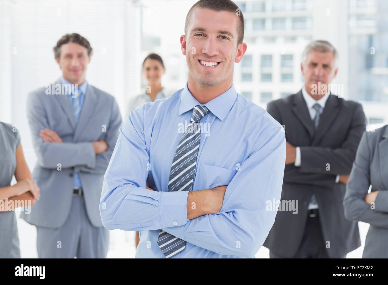 Smiling business team standing with arms crossed Stock Photo - Alamy