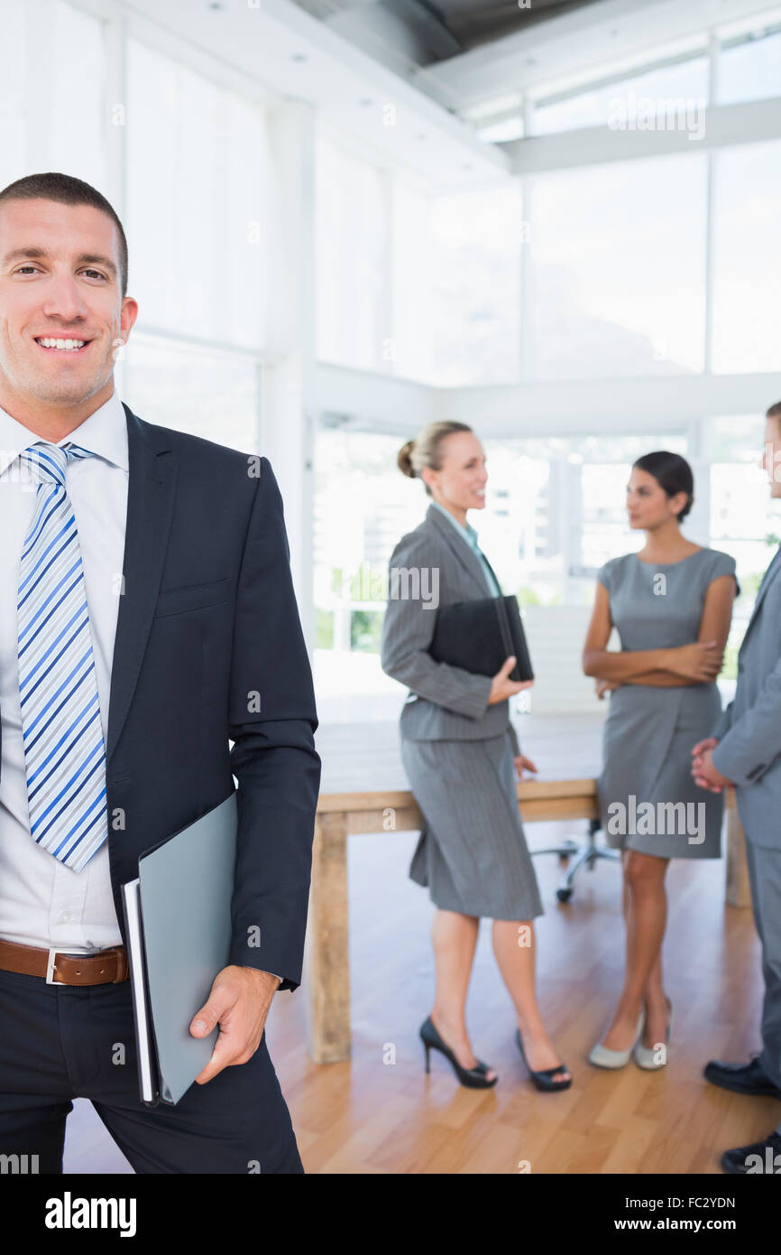 Businessman smiling at camera with colleagues behind him Stock Photo ...
