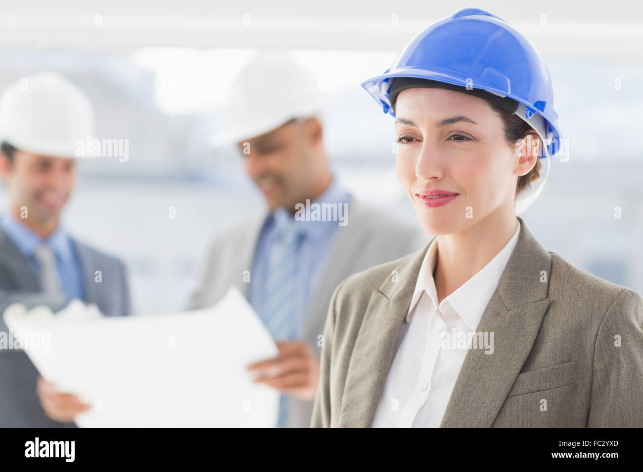 Businessmen and a woman with hard hats and holding blueprint Stock ...