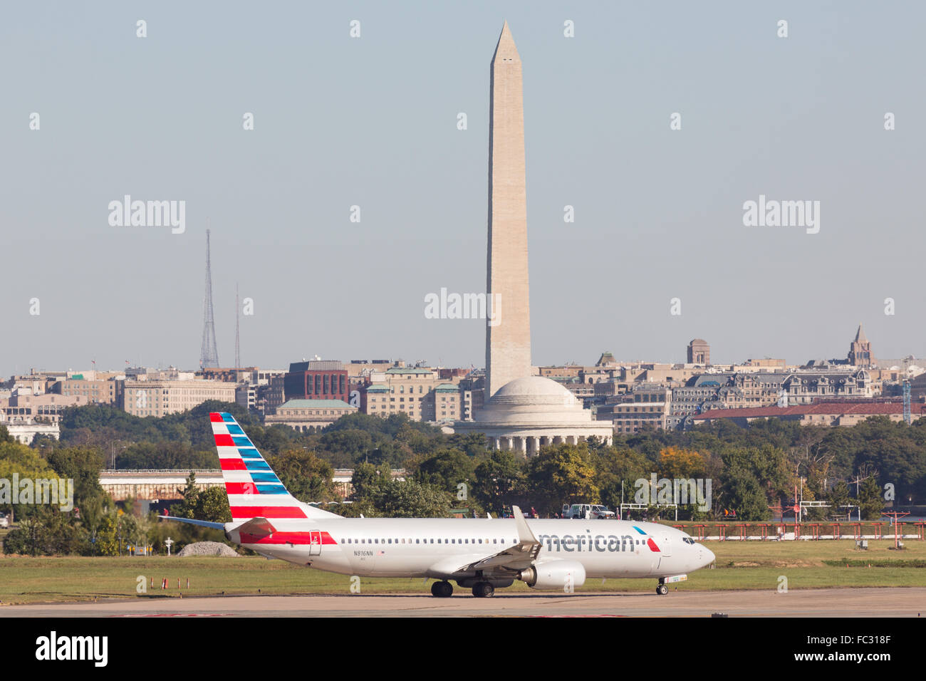 An American Airlines plane taxis to the runway with the Washington Monument and Jefferson Memorial in the background at Reagan National Airport across the Potomac from Washington during operations October 5, 2014 in Arlington, Virginia. Stock Photo