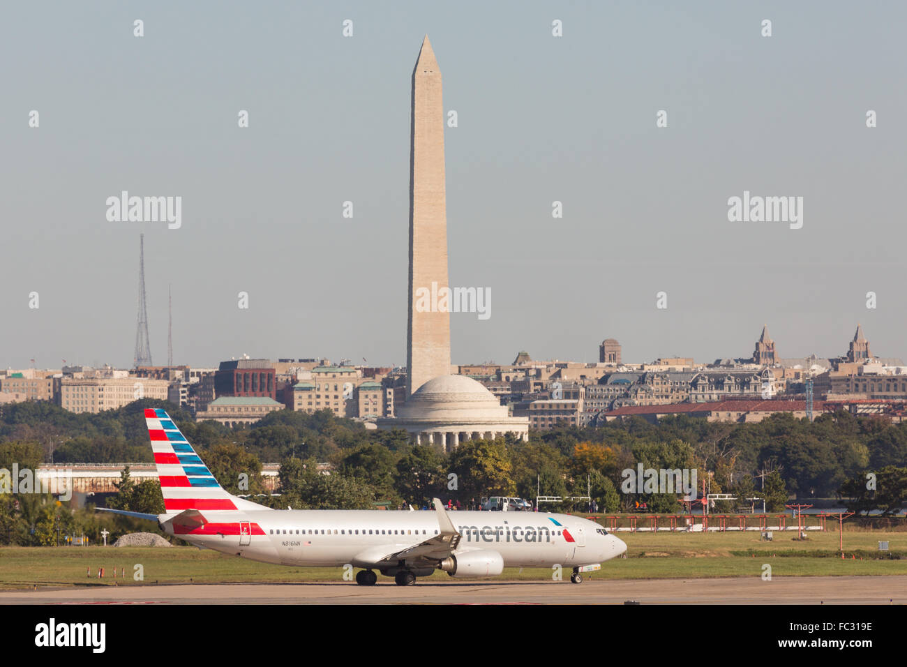 An American Airlines plane taxis to the runway with the Washington Monument and Jefferson Memorial in the background at Reagan National Airport across the Potomac from Washington during operations October 5, 2014 in Arlington, Virginia. Stock Photo