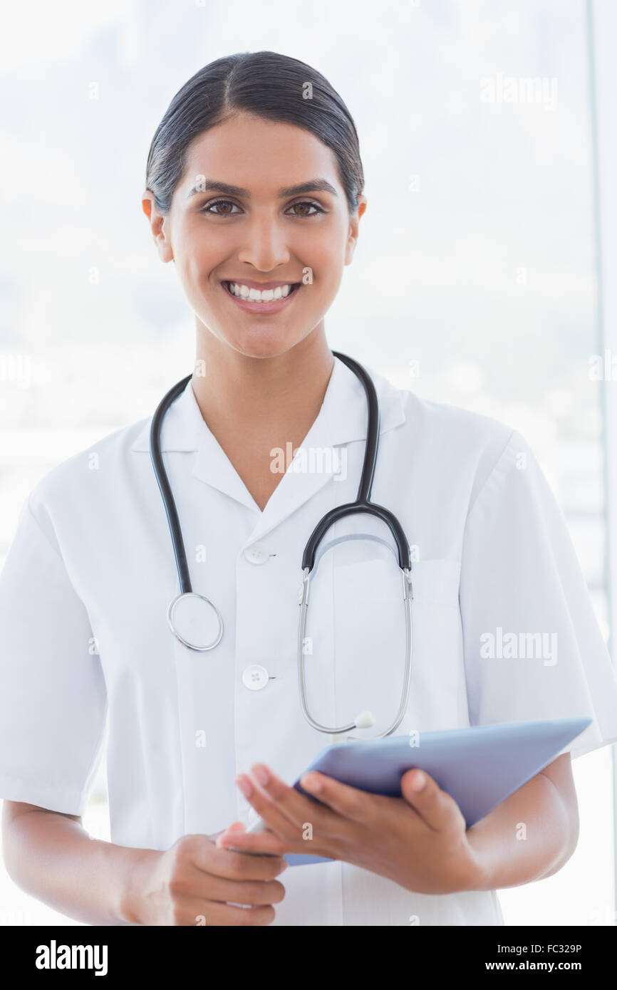Happy doctor holding clipboard and smiling at camera Stock Photo - Alamy
