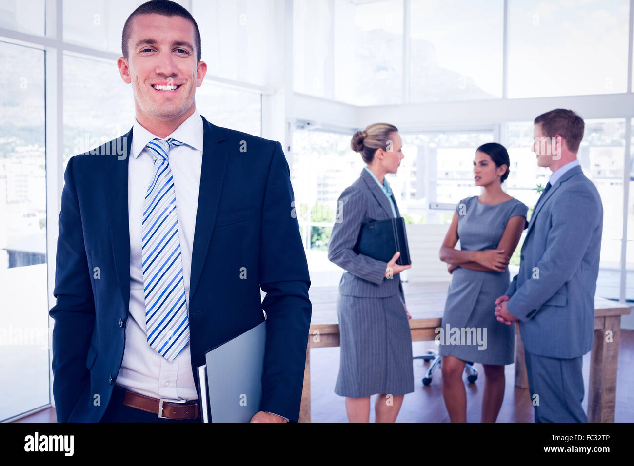 Businessman smiling at camera with colleagues behind him Stock Photo ...