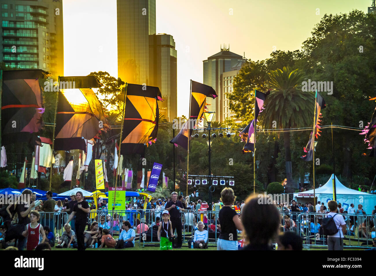 Crowds gathered in Alexandra Gardens at Melbourne Festival flags waving in the sunset Stock Photo