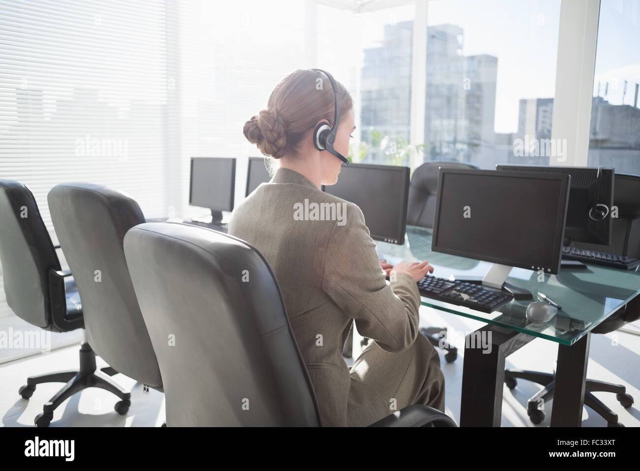 Smiling businesswoman with headset using computers Stock Photo