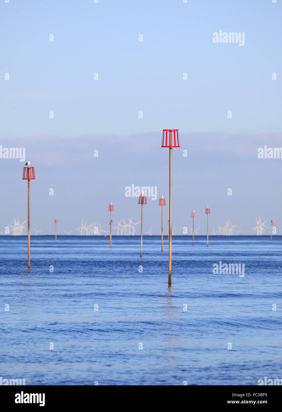 Markers for submerged groynes and wind turbines in a calm blue sea. Stock Photo