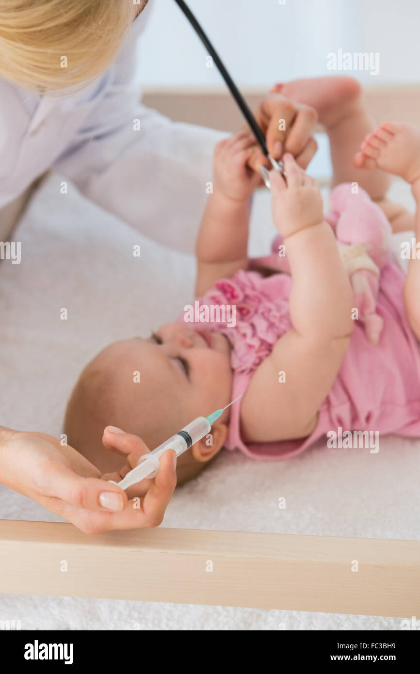 Beautiful baby girl and doctor using syringue and needle Stock Photo