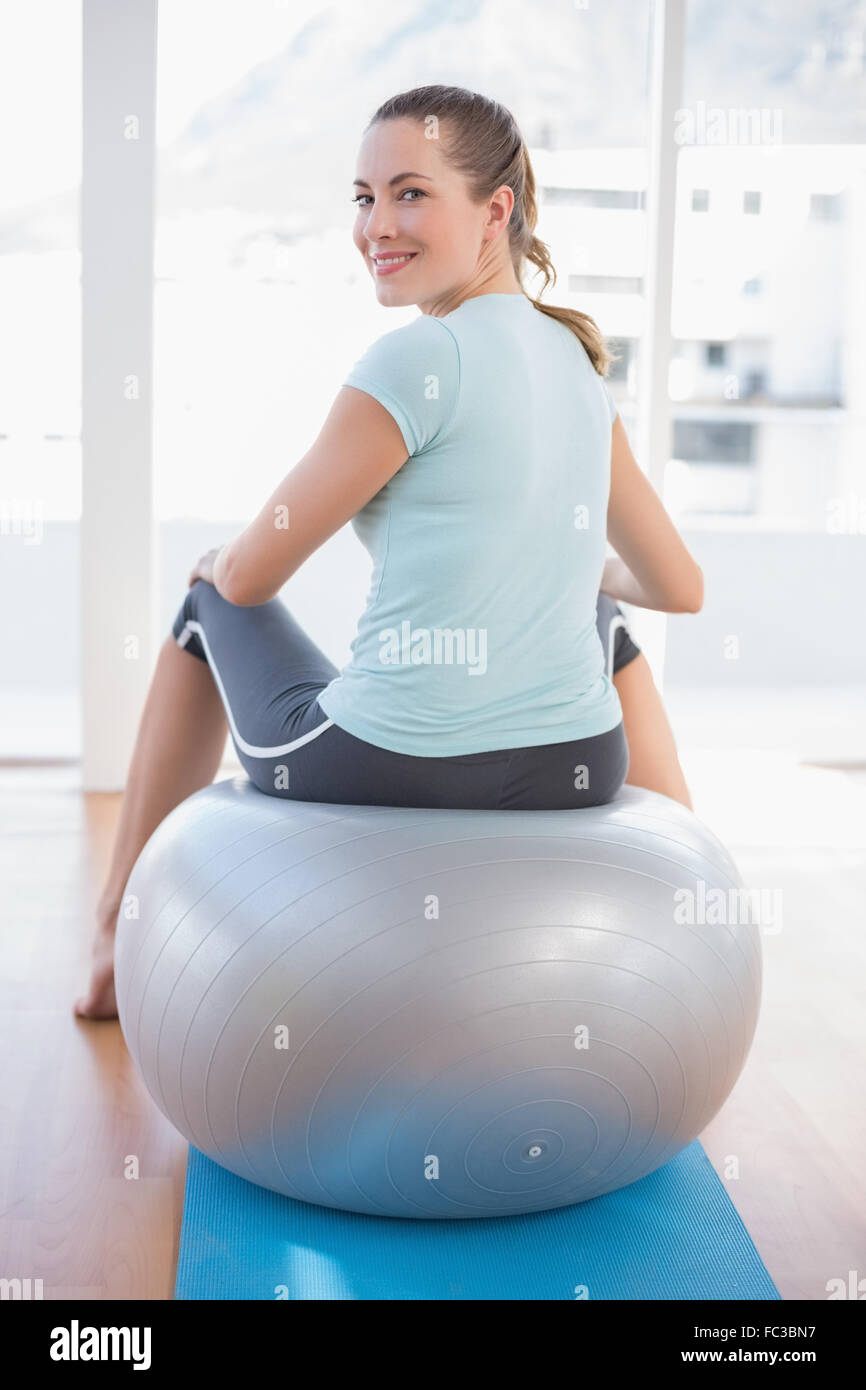 Woman looking at camera and sitting on exercise ball Stock Photo - Alamy