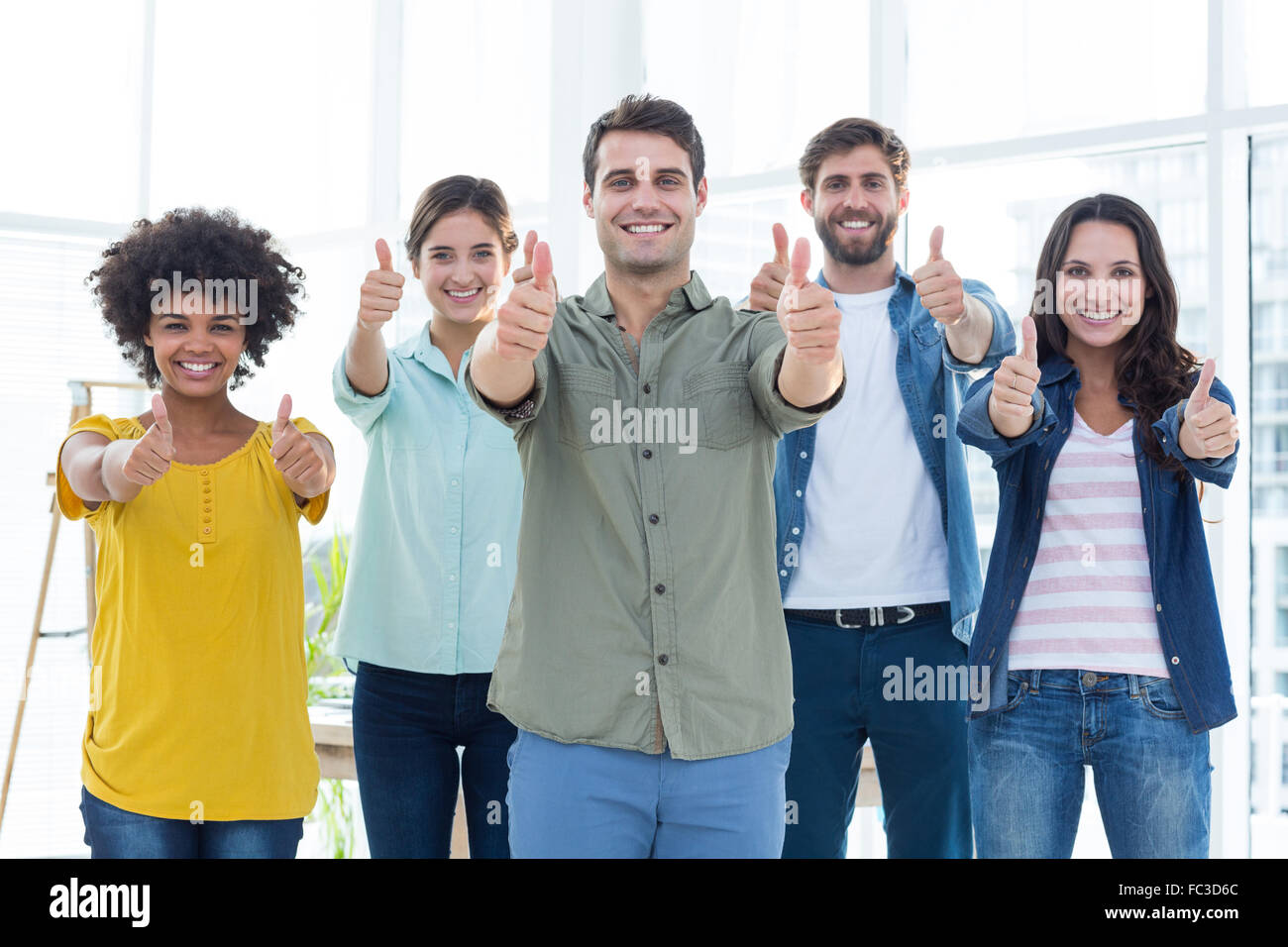 Young creative business people gesturing thumbs up Stock Photo - Alamy