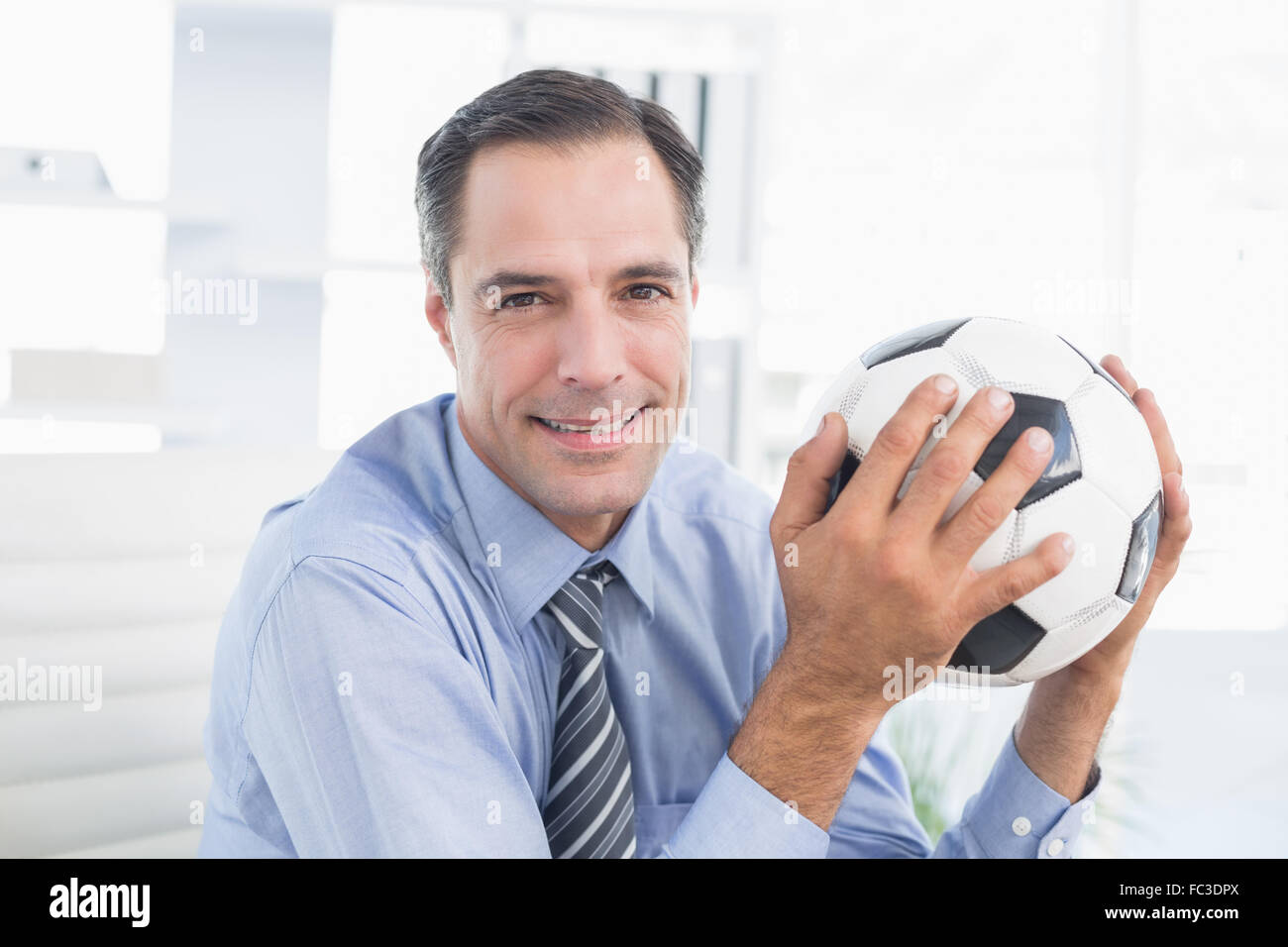 Smiling businessman looking at camera with foot ball Stock Photo - Alamy