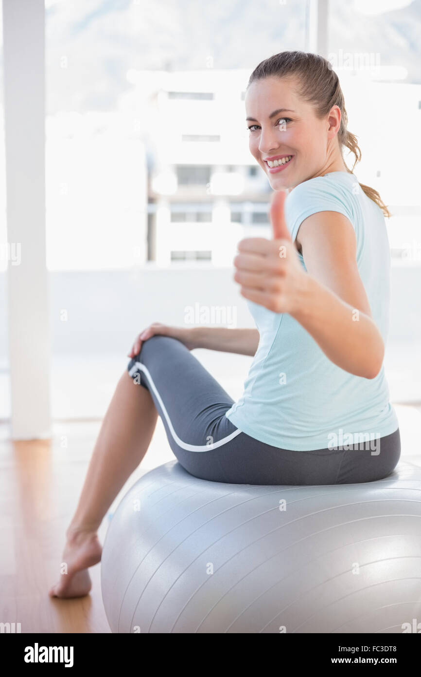 Woman looking at camera and sitting on exercise ball Stock Photo - Alamy