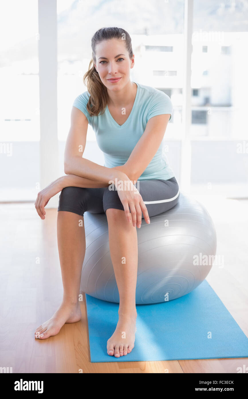 Woman looking at camera and sitting on exercise ball Stock Photo - Alamy