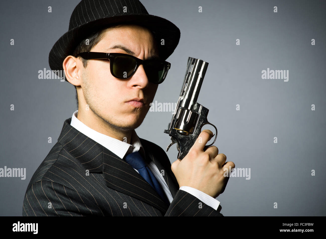 Young man in classic striped costume holding gun isolated on gray Stock Photo