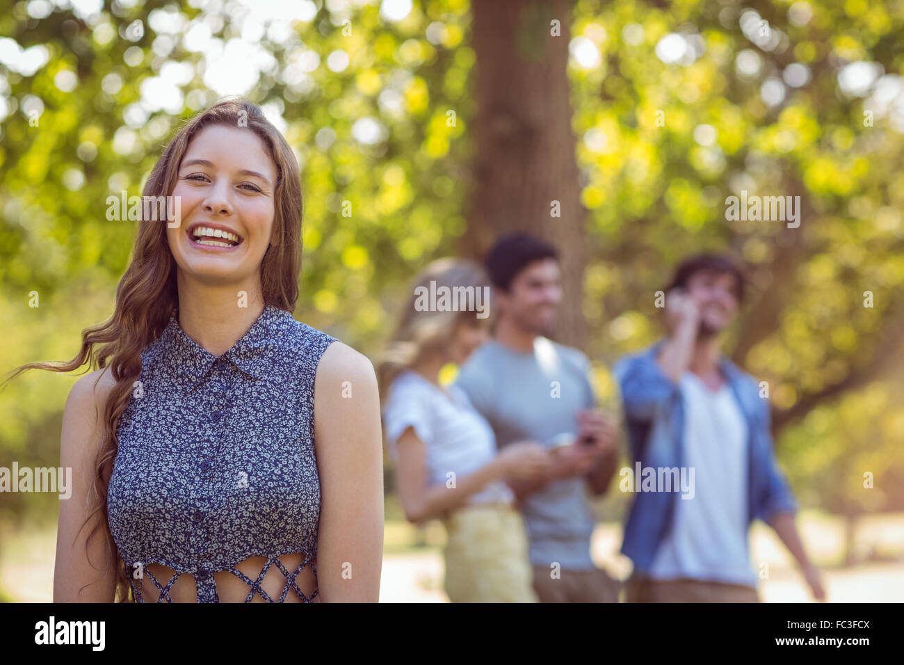 Happy friends in the park using their phones Stock Photo - Alamy