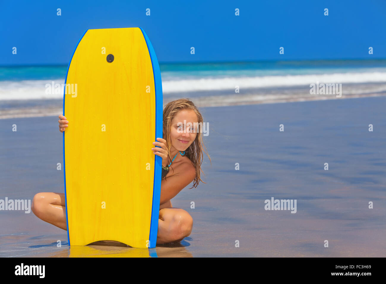 Happy girl - young surfer with bodyboard has fun on sea sand beach with waves. Stock Photo