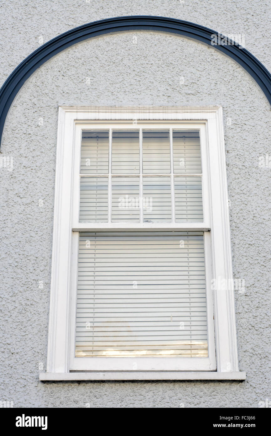 Wooden rectangular window with curved eyebrow accent on stucco wall Stock Photo