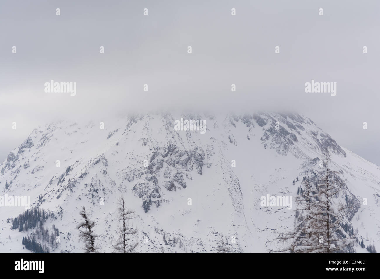 snowy mountain peaks shrouded in mist has Stock Photo