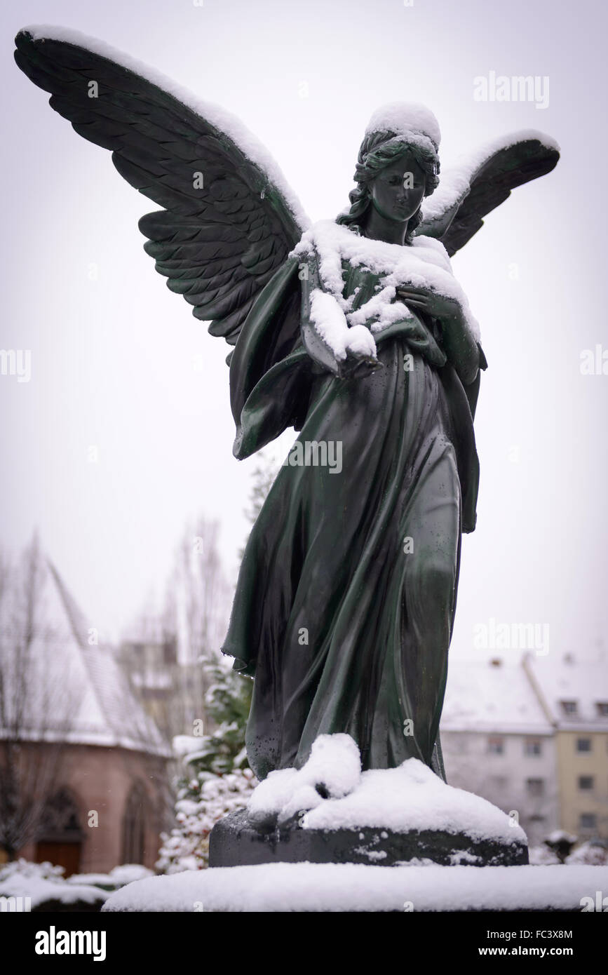 Statue of an sorrowing angel covered with snow at the cemetery in Nuremberg, Germany Stock Photo