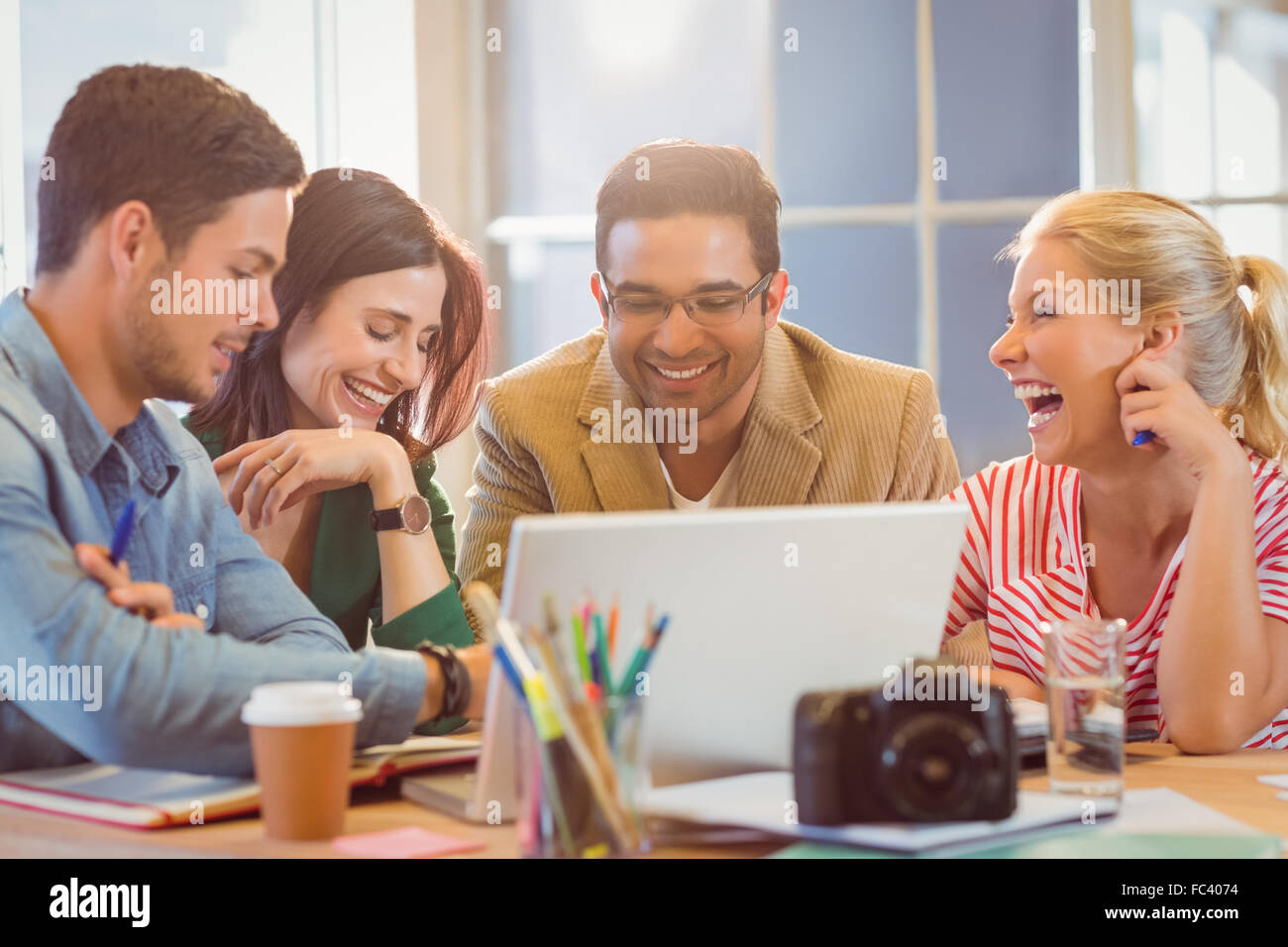 Happy creative business team using laptop in meeting Stock Photo - Alamy