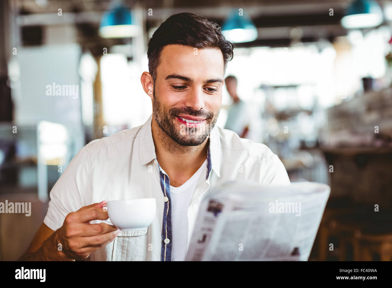 Young man having cup of coffee reading newspaper Stock Photo Alamy