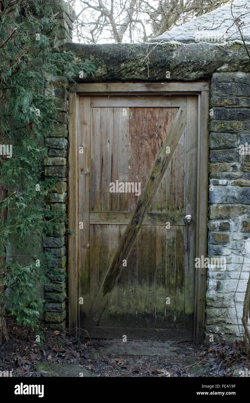 Weathered wooden door in a stone wall Stock Photo