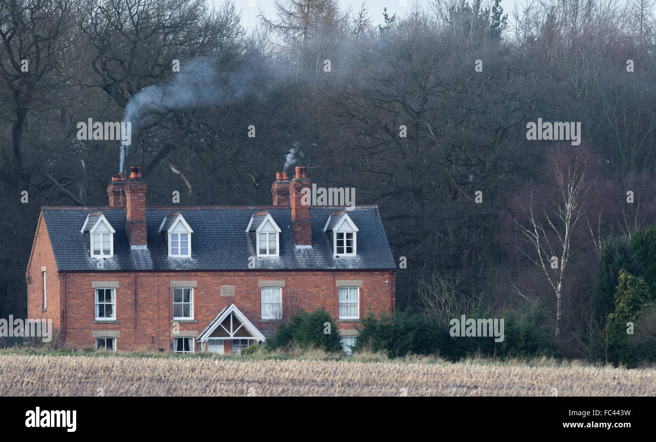 Smoke drifting from brick built country estate cottagers in late winters evening. Stock Photo