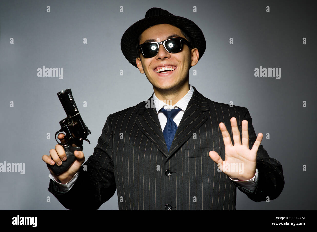 Young man in classic striped costume holding gun isolated on gra Stock Photo