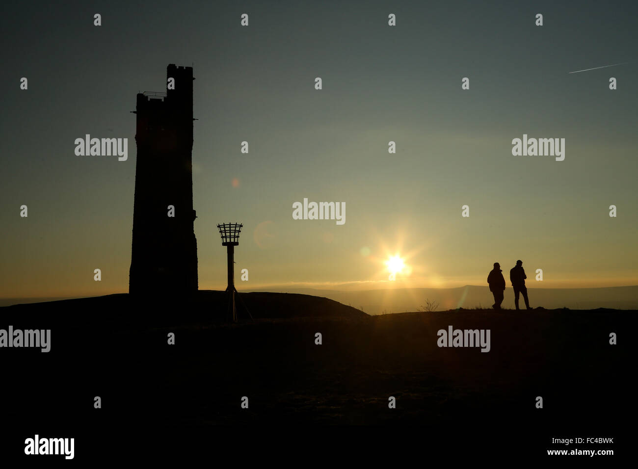 Huddersfield, West Yorks, UK. 20th January, 2016. People watch the sun set over Huddersfield in West Yorkshire, UK, next to the Victoria Tower atop Castle Hill. The UK saw temperatures plummet to below -12 degrees for the second day in a row despite the bright sunny weather across much of the country. Credit:  Ian Hinchliffe/Alamy Live News Stock Photo