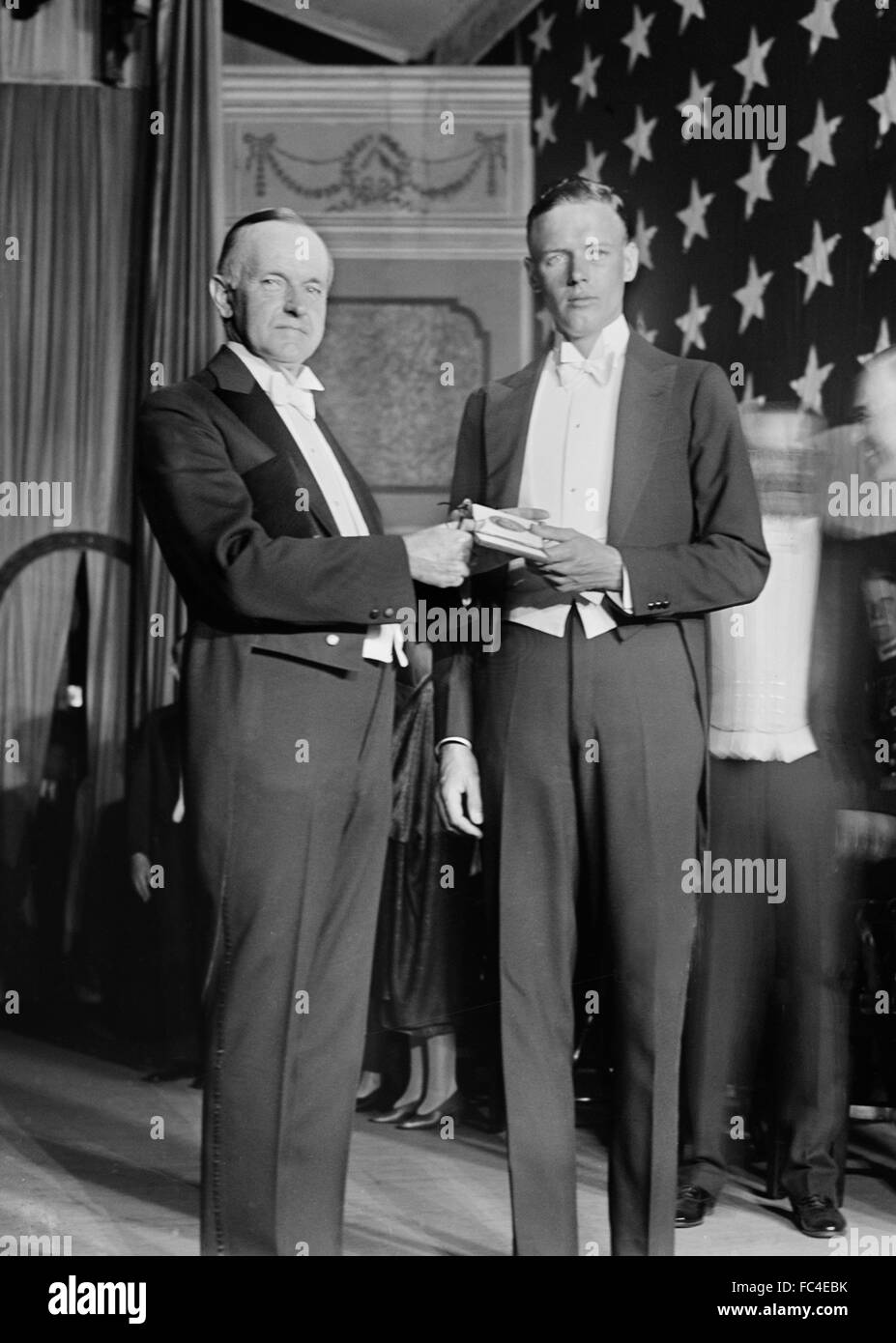 Calvin Coolidge and Charles Lindbergh. On June 11, 1927, President Calvin Coolidge presents Colonel Charles Lindbergh with the first Distinguished Flying Cross medal for his solo non-stop flight across the Atlantic Ocean, Stock Photo